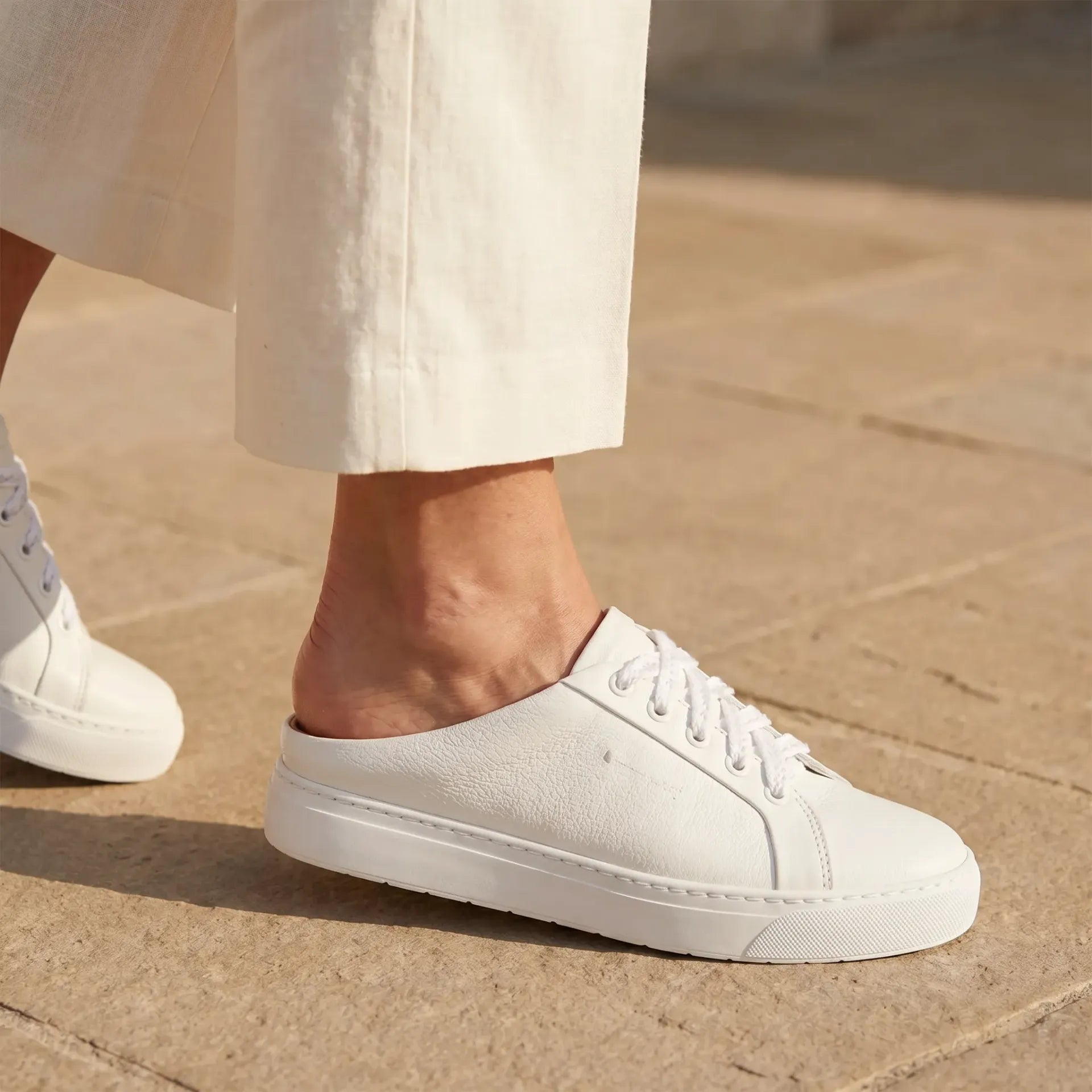 Lincoln II White Tumbled — walking foot close-up, open backless mule silhouette, ivory linen trousers